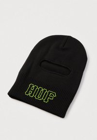 Balaclava neagră tricotată cu o deschidere pentru un singur ochi și broderie cu logo-ul "HUF" de culoare verde neon pe marginea inferioară frontală.