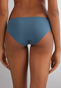 Blå sömlös hipsterunderkläder med en mjuk textur och låg midja, med en minimalistisk skärning och inga synliga sömmar.
