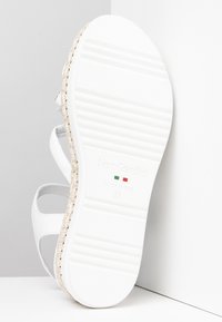 Sandaletta bianca con suola bianca testurizzata e dettagli in juta intrecciata. Design leggero con cinturini aperti. Marcata "NeroGiardini" e taglia 37.