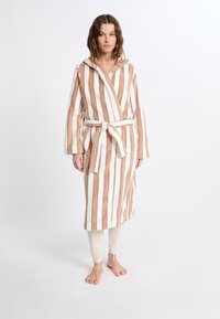 Koupací plášť s kapucí, se střídajícími svislými bílými a světle hnědými pruhy. Měkká tkanina, opasek v oblasti pasu a dlouhé rukávy. Žádné další detaily.