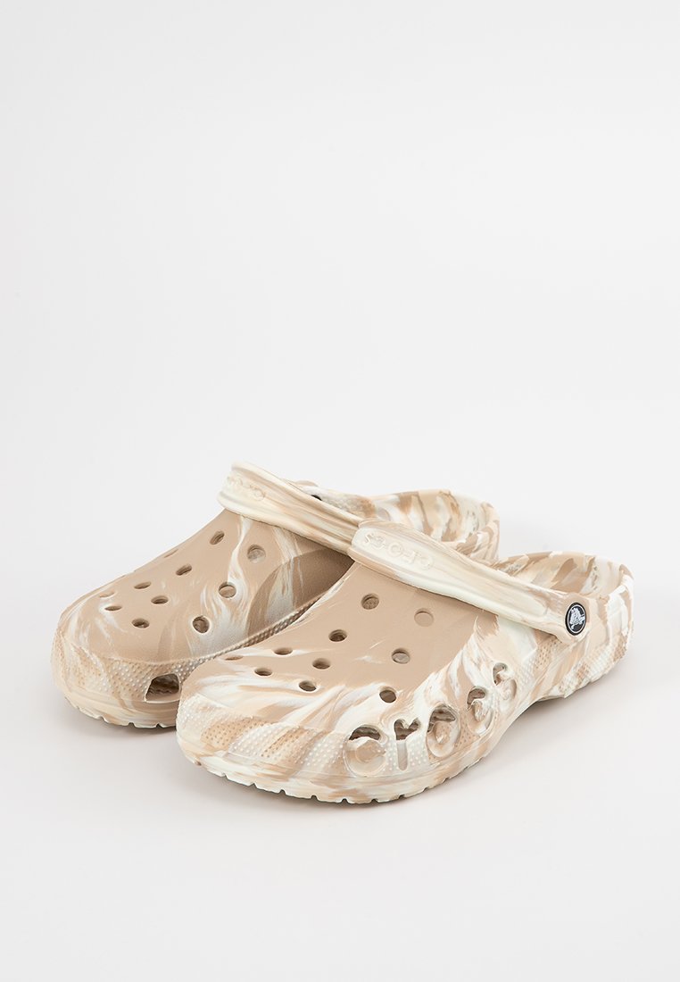 Zuecos en color beige y crema con un diseño veteado, orificios de ventilación, una correa trasera y logotipo en relieve. Fabricados con un material sintético ligero y duradero.