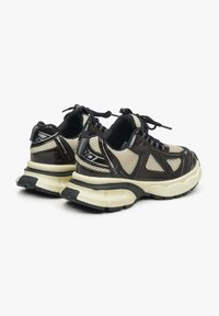 Czarno-brązowe sneakersy z siateczkowymi i lakierowanymi nałożeniami, teksturowane podeszwy, sznurowane zapięcie oraz elastyczne amortyzowanie dla wsparcia.