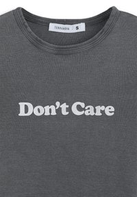 T-shirt in cotone grigia con collo rotondo, con la scritta "Non mi interessa" stampata in grande carattere bianco e in grassetto sulla parte anteriore. Tag della taglia: S.