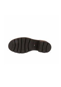 Suela de goma negra con textura, que presenta surcos pronunciados y un pequeño detalle de la bandera italiana de color. Superficie lisa, diseño flexible.