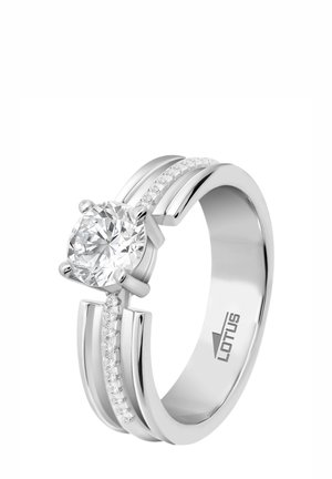 Bague en argent présentant une grande pierre centrale ronde et claire, flanquée de deux bandes avec de petits diamants incrustés d'un côté. Marquée "LOTUS".
