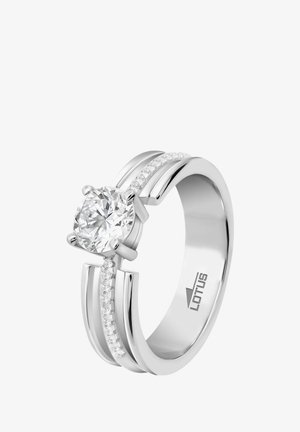 Bague en argent présentant une grande pierre centrale ronde et claire, flanquée de deux bandes avec de petits diamants incrustés d'un côté. Marquée "LOTUS".