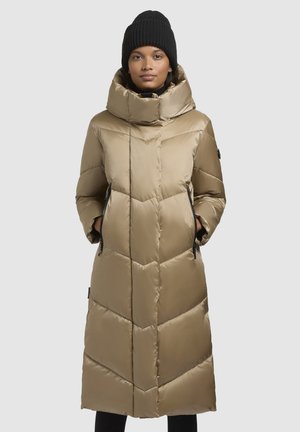 Long, beige puffer coat with a high collar, chevron quilting, two side pockets, and a smooth, shiny finish. Worn with a black knit beanie.