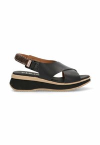 Sandalia de piel negra tipo slingback con diseño de correas cruzadas, suela acolchada y un acento metálico texturizado en la correa trasera ajustable.