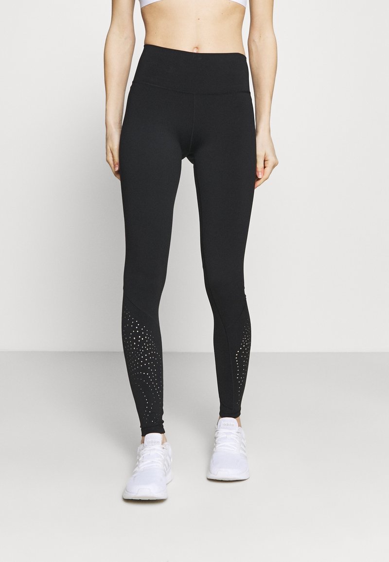 Leggings noirs en tissu extensible avec une taille haute. Présentent des accents texturés avec des motifs cloutés près de la cheville.