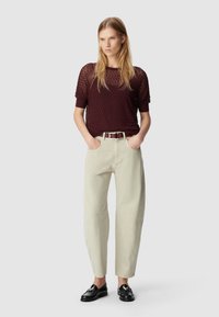 Bordeaux gemêlede tricot top met korte mouwen, gecombineerd met lichtbeige wijde broek en zwarte leren instapschoenen. Bruine riem inbegrepen.