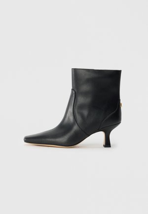 Stivale in pelle nera alla caviglia con punta appuntita e tacco piccolo e quadra. Presenta una superficie liscia e un design minimalista con dettagli sulle cuciture laterali.