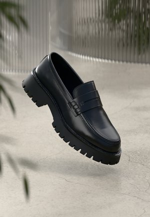 Μαύρες δερμάτινες εσπαντρίγιες με χοντρή τρακτερωτή σόλα, διαθέτοντας διακοσμητική λωρίδα και λεπτομέρεια ραφής. Λείος υφής με γυαλιστερό φινίρισμα.