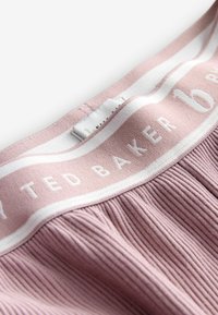 Rozā ribota jostu josla ar baltā krāsā uzrakstu "Ted Baker". Virspusē izceļas balta svītra. Mīksta tekstūra, izstrādāta ērtībai.