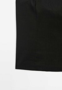 Section de jupe en tissu noir montrée sur un fond blanc avec un ourlet droit et une texture verticale subtile.