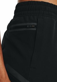 Svarta atletshorts i ett texturerat tyg, med en synlig dragkedjeförsedd ficka och en elastisk midjeband för komfort.