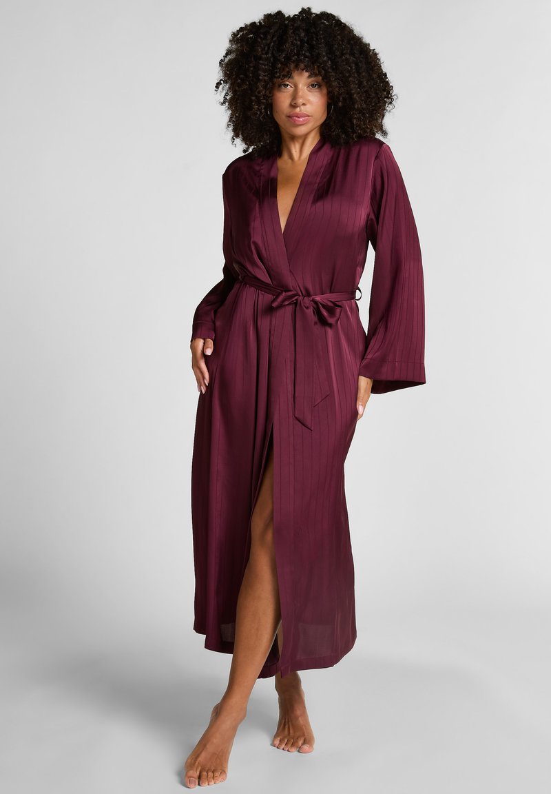 Μακρύ ρουμπινί σατέν μανδύας με σχέδιο περιτυλίγματος, μακριά μανίκια και ζώνη στη μέση. Διαθέτει κάθετη ραβδωτή υφή και σκίσιμο μέχρι το μηρό.