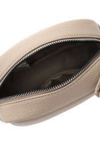 Pochette en cuir beige avec une surface texturée, dotée d'une fermeture éclair en argent et d'un intérieur doublé en tissu. Ouverte pour montrer l'espace intérieur.