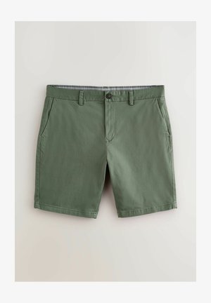 Zaļi kokvilnas šorti ar plakanu priekšpusi, divām sānu kabatām un pogu aizdari. Ar rakstainu jostasvietu. Gluda tekstūra.