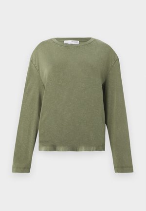 Cămașă cu mânecă lungă, de culoare verde măsliniu, cu un croi lejer și tiv ușor scurtat, pe un fundal alb uniform.