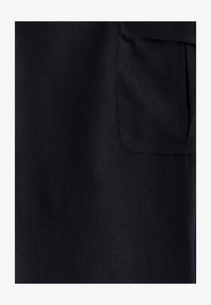 Nahaufnahme von schwarzem Stoff mit einer rechteckigen genähten Tasche auf der rechten Seite.