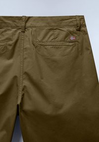 Dos d’un pantalon vert olive avec passants de ceinture, deux poches passepoilées et un petit écusson de drapeau rouge, blanc et bleu au-dessus de la poche droite.