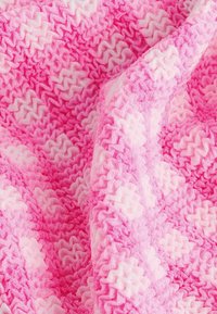 Stickad filt med en vågig struktur i nyanser av rosa och ljusrosa, med ett lager av zigzag-mönster, mjukt och lätt material.
