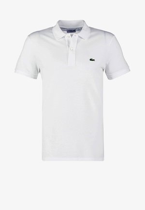 Polo blanc en coton, avec un col à trois boutons, des manches courtes et un logo crocodile brodé vert sur la poitrine gauche.