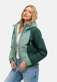 Color-blocked bomber jacket in light and dark green, featuring a zip front, hood, elastic cuffs, and two side pockets. Soft fabric texture.