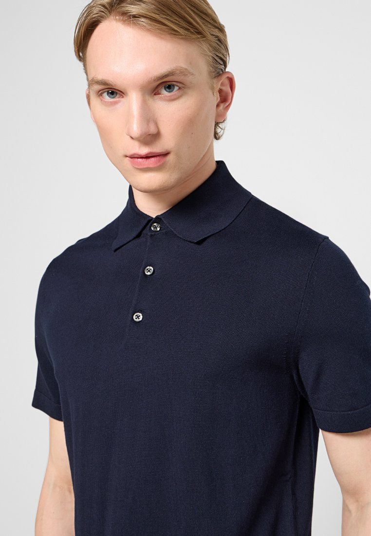 Granatowa koszulka polo wykonana z teksturowanej tkaniny, z kołnierzykiem, krótkimi rękawami i trzema guzikami z kontrastującymi guzikami.