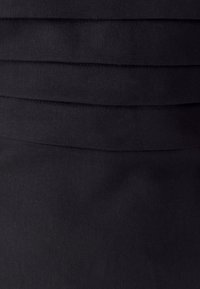 Black skirt with a textured fabric and horizontal pleats. Features clean lines and a smooth finish, designed for a fitted silhouette.