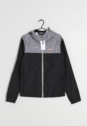 Svart och grå huva med dragkedja framtill, med en texturerad grå överdel, slät svart underdel och två sidofickor.