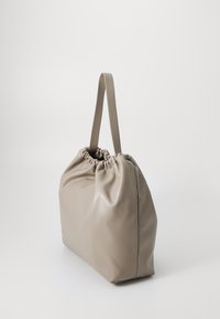 Saco de couro taupe suave com parte superior franzida e duas alças planas para o ombro, contra um fundo claro e liso.