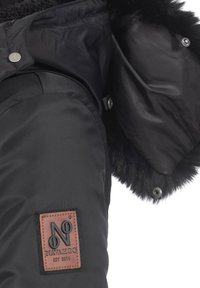 Schwarze gepolsterte Jacke mit einem Kunstfellkragen. Verfügt über ein braunes Logo-Patch, Druckknöpfe und eine glatte Textur. Enthält Seitentaschen.