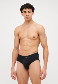 Schwarze Unterhose aus elastischem Stoff mit glatter Textur. Verfügt über einen festen Bund mit dezenten Logo-Akzenten auf der Vorderseite.