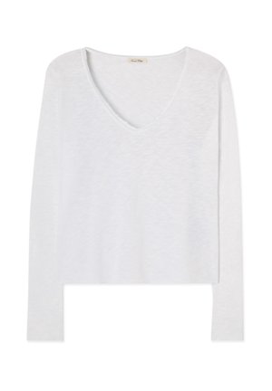 Vitt långärmat V-ringad tröja med lätt strukturerat tyg och kant med rå kant, visad mot en enfärgad bakgrund.