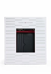 Schwarze Lederbörse mit strukturiertem Finish in einer weißen und grauen Box, mit Markenlogo und rotem Innenfutter. Enthält Kartenfächer und ein elegantes Design.