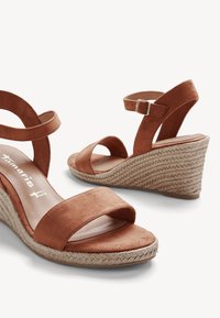 Sandales compensées en suède marron avec un design à deux brides. Dotées d'une semelle intermédiaire en jute tressé et d'une bride à boucle à la cheville. Semelle intérieure en cuir lisse.