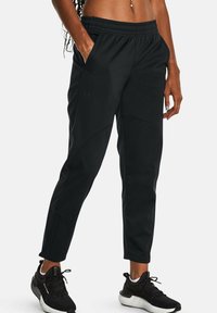 Zwarte sportieve joggers met een elastische tailleband, zijzakken en contrasterende stiksels. Het materiaal lijkt glad met een strakke pasvorm.