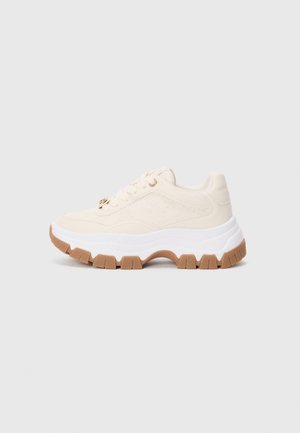 Sneakers chunky in crema con suola intermedia bianca e suola esterna in gomma marrone. Presentano dettagli in rilievo e fori per i lacci rotondi con accenti metallici.