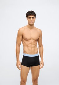 Juodos bokserio kelnaitės su šviesiai mėlynu Calvin Klein juosmeniu, pagamintos iš glotnios, tamprios medžiagos, su prigludusia forma ir vidutinio ilgio iki šlaunų.