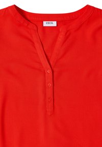 Blusa di cotone rossa con scollatura a V, patta davanti con cinque bottoni e maniche corte. Texture liscia con una finitura dai colori vivaci.