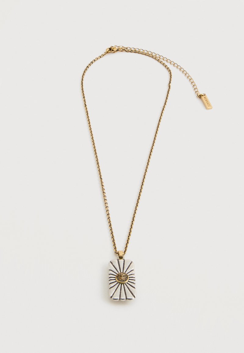 Collier chaîne en or avec pendentif rectangulaire en argent présentant un design de rayons de soleil et un emblème central Méduse en or, fermoir ajustable avec étiquette de marque.
