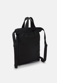 Zaino nero realizzato in tessuto resistente, dotato di due manici superiori e cinghie laterali regolabili, con un design minimalista e senza loghi visibili.