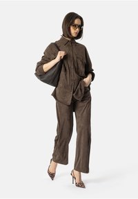 Brun semsket skjorte og matchende bukser med to brystlommer, kombinert med leopardmønstret sandlett med hæl og en svart tote-bag.