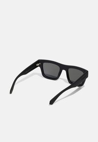 Occhiali da sole neri con forma rettangolare, finitura opaca, lenti scure polarizzate e branding minimalista sulle tempie.