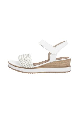 Sandale compensée blanche avec une sangle avant tissée, une sangle de cheville réglable, une semelle intercalaire texturée et une base en bois contrastée.