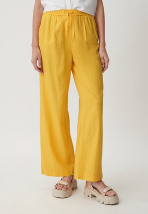 Pantalons larges jaunes avec une taille élastique et un détail à cordon de serrage. Fabriqués en tissu léger, présentant une coupe décontractée et une texture lisse.