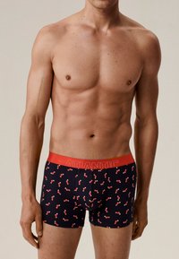 Męskie bokserki w kolorze granatowym z czerwonym ściągaczem. Ozdobione wzorem małych czerwonych skarpetek. Miękki, elastyczny materiał zapewniający komfort i dopasowanie.