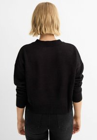 Suéter de punto negro con cuello redondo, diseño corto y mangas largas. La tela parece suave y texturizada, adecuada para un uso casual.