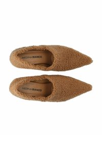 Tanschoenen met een puntige neus, gemaakt van een textuur met een fluffy buitenmateriaal en een gladde binnenvoering, met de merknaam "MEDINA BIANCO" aan de binnenkant.